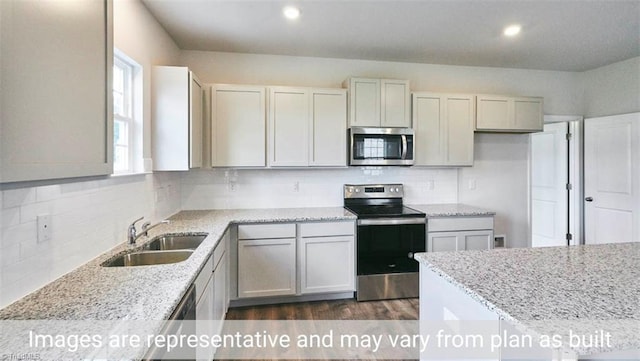 kitchen featuring sink, stainless steel appliances, light stone counters, and backsplash