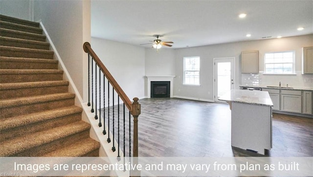 unfurnished living room featuring sink, dark hardwood / wood-style floors, and ceiling fan