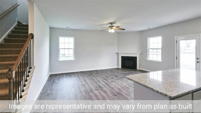 unfurnished living room featuring hardwood / wood-style flooring, a wealth of natural light, and ceiling fan