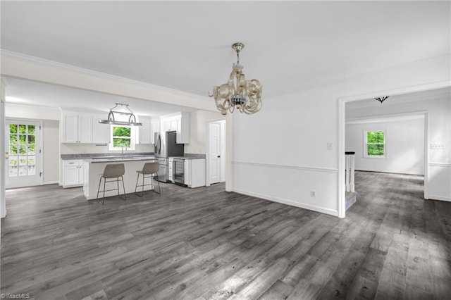 2104 Laura Ln, High Point, NC 27262 - unfurnished living room featuring dark wood-style flooring, a chandelier, healthy amount of natural light, crown molding, and baseboards