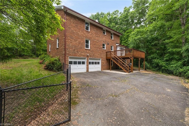 2104 Laura Ln, High Point, NC 27262 - view of side of home with stairs, asphalt driveway, a garage, a deck, and brick siding
