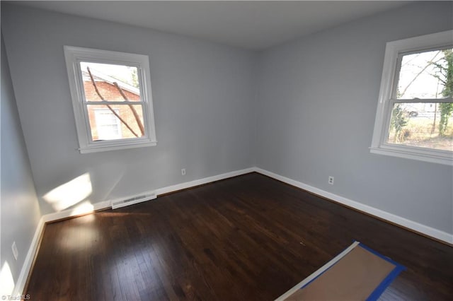 spare room featuring dark hardwood / wood-style floors and plenty of natural light