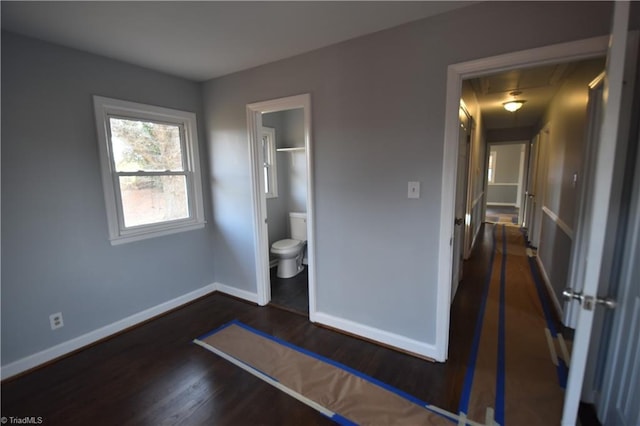 unfurnished bedroom featuring connected bathroom, a closet, and dark hardwood / wood-style floors