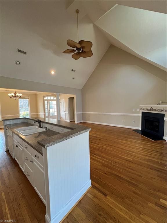 kitchen with dark wood-type flooring, ceiling fan with notable chandelier, a sink, open floor plan, and white cabinetry