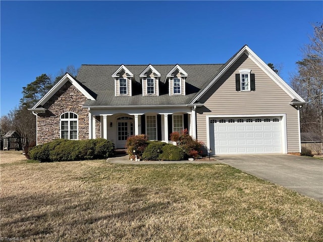 cape cod home featuring a front lawn, a porch, roof with shingles, concrete driveway, and a garage