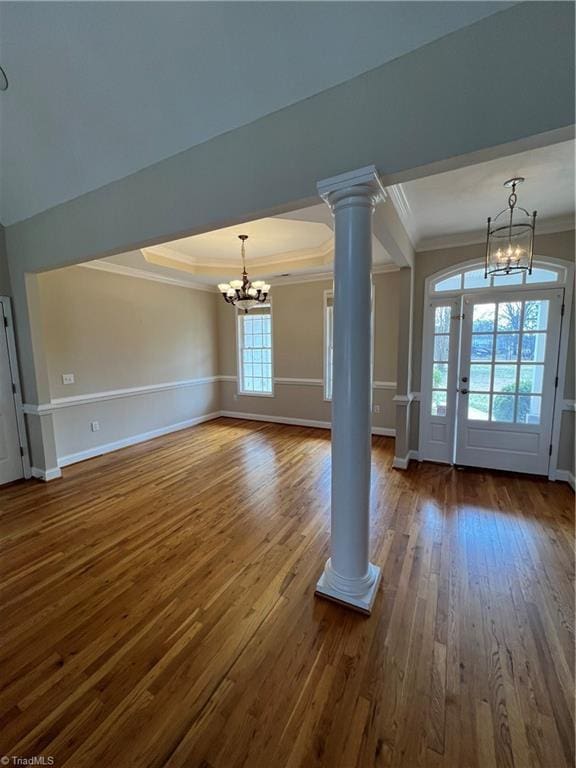 interior space featuring ornamental molding, baseboards, a chandelier, dark wood-style flooring, and ornate columns