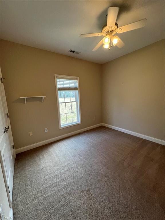 unfurnished room with dark colored carpet, visible vents, baseboards, and a ceiling fan