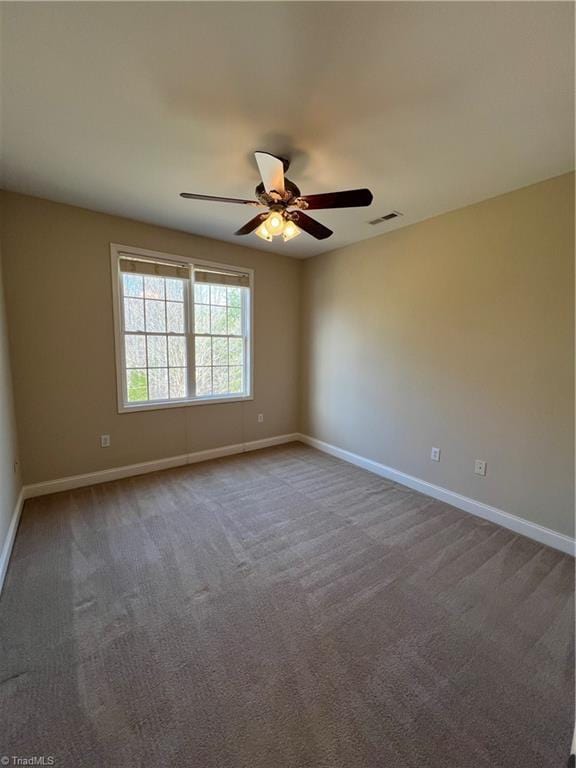 empty room featuring carpet, a ceiling fan, visible vents, and baseboards