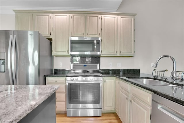 4507 Brandt Ridge Dr, Greensboro, NC 27455 - kitchen featuring dark stone counters, stainless steel appliances, a sink, and light wood-style floors