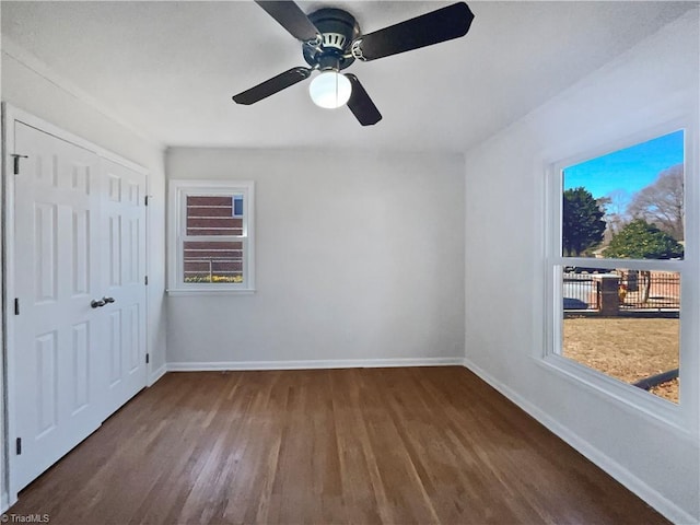 unfurnished bedroom with multiple windows, dark hardwood / wood-style flooring, ceiling fan, and a closet