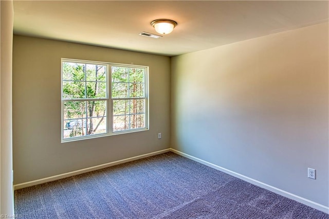 spare room with carpet floors, visible vents, and baseboards