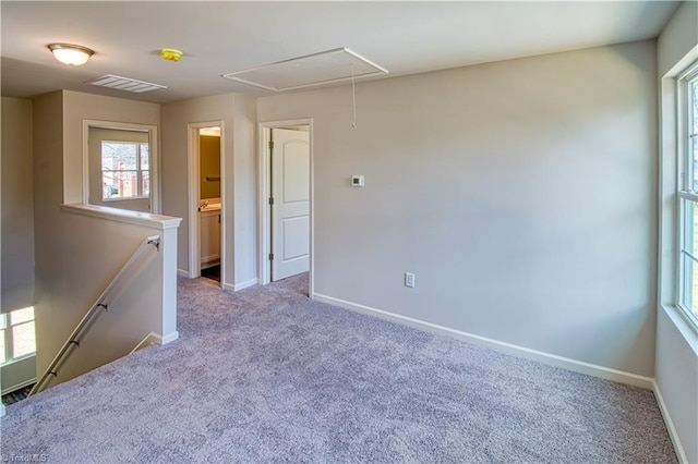 empty room with light carpet, attic access, visible vents, and baseboards