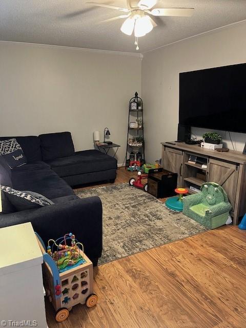 living area with a ceiling fan, a textured ceiling, and wood finished floors