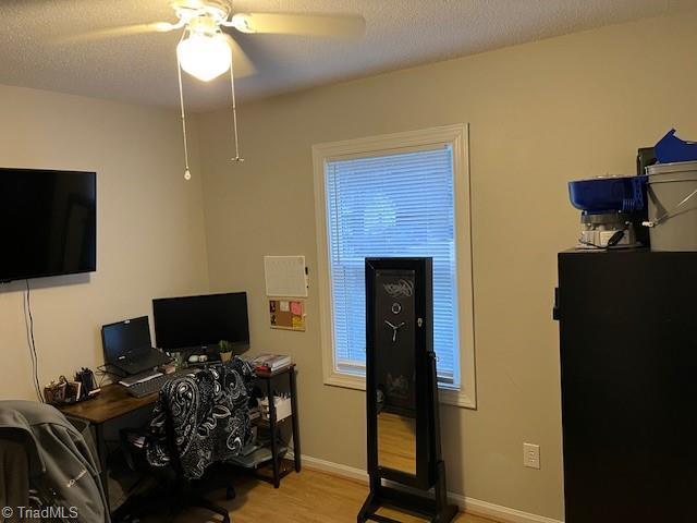 office with light wood-type flooring, ceiling fan, baseboards, and a textured ceiling