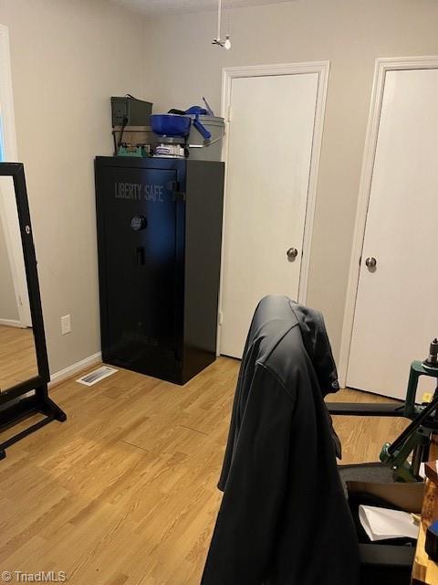 office area with light wood-type flooring, baseboards, and visible vents