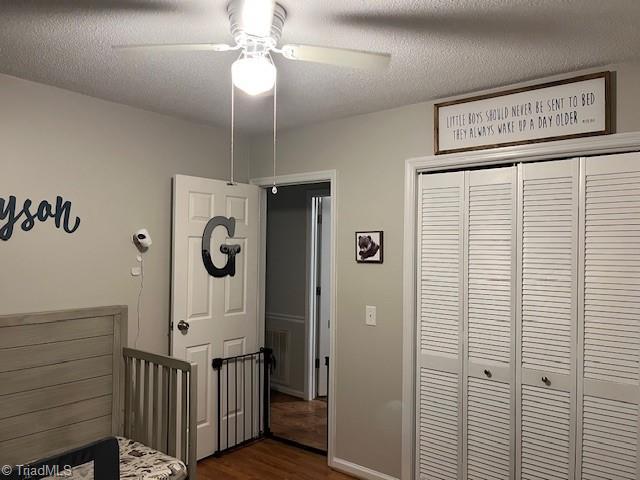 bedroom featuring a textured ceiling, dark wood-style flooring, a closet, and ceiling fan