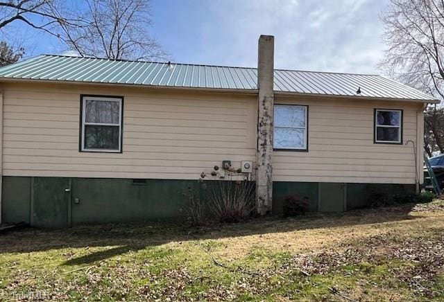 view of home's exterior featuring metal roof, a yard, crawl space, and a chimney