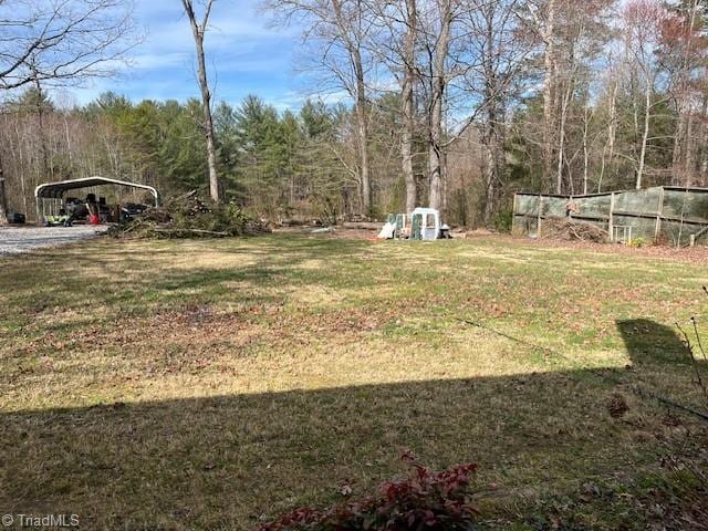 view of yard with a detached carport and a wooded view