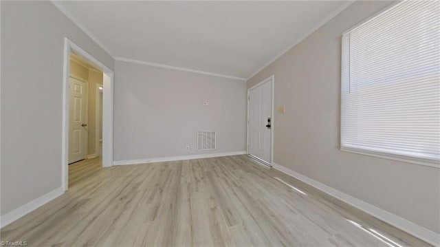 empty room with ornamental molding, visible vents, and baseboards