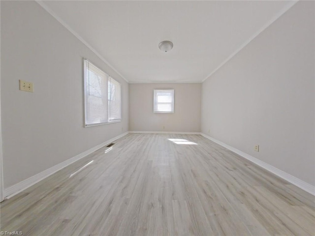 empty room with visible vents, crown molding, light wood-style flooring, and baseboards