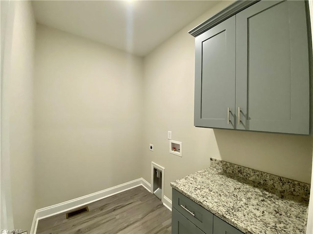 laundry area featuring hardwood / wood-style flooring, hookup for a washing machine, cabinets, and hookup for an electric dryer