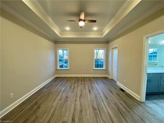 spare room featuring a tray ceiling, ceiling fan, wood-type flooring, and ornamental molding