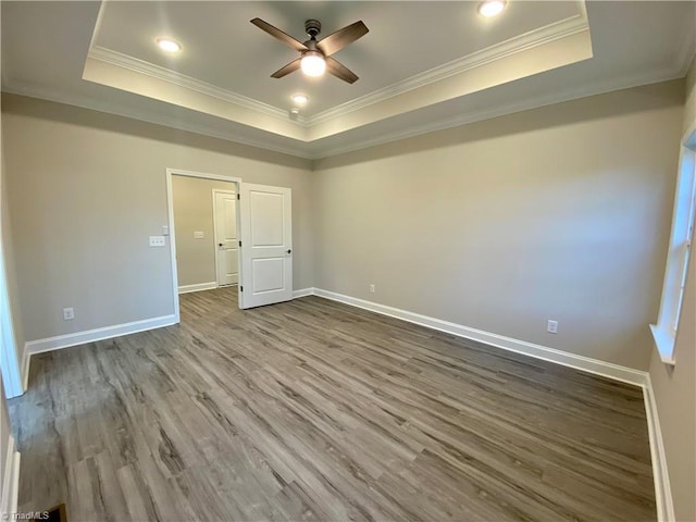 unfurnished bedroom featuring hardwood / wood-style floors, ceiling fan, crown molding, and a tray ceiling