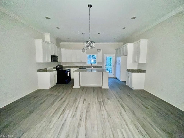 kitchen featuring white cabinets, light wood-type flooring, decorative light fixtures, and a kitchen island