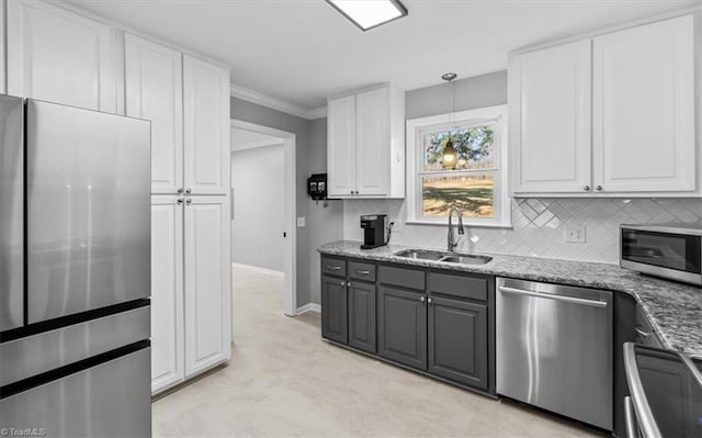 kitchen with light stone counters, a sink, white cabinetry, appliances with stainless steel finishes, and decorative backsplash