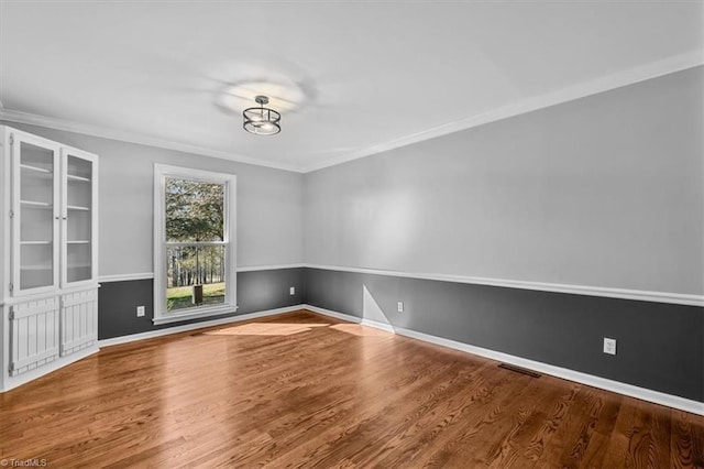 unfurnished room featuring ornamental molding, baseboards, and wood finished floors