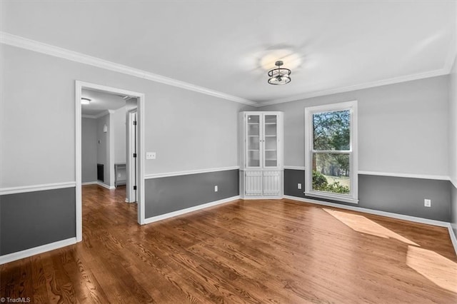 empty room with crown molding, baseboards, and wood finished floors