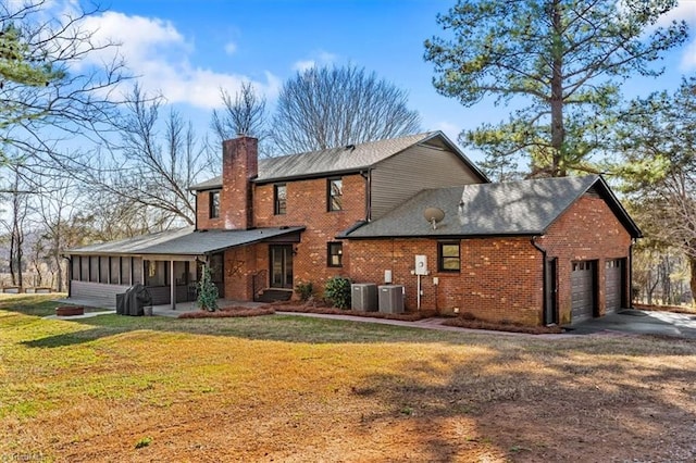 back of house with an attached garage, central air condition unit, a sunroom, a yard, and a chimney