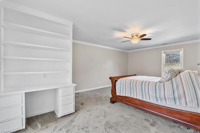 carpeted bedroom featuring ornamental molding, built in study area, baseboards, and a ceiling fan