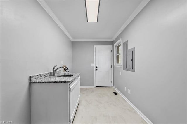 clothes washing area with ornamental molding, visible vents, a sink, and baseboards