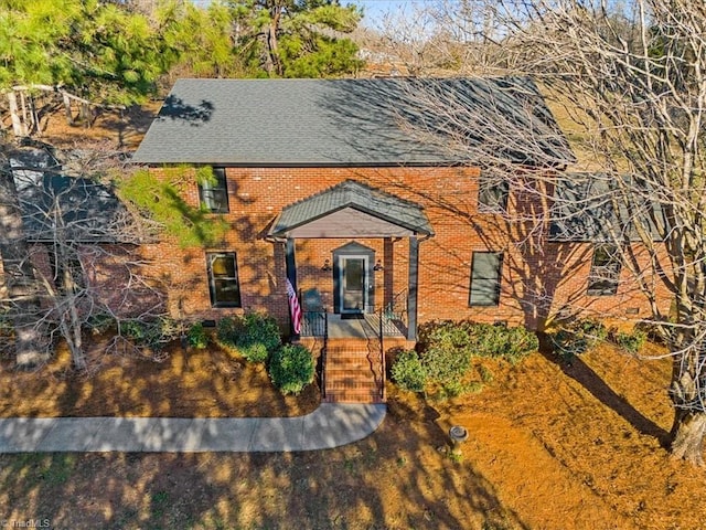 view of front of house featuring brick siding and roof with shingles