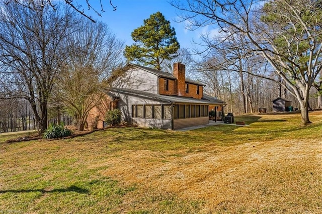 back of property featuring a lawn, a chimney, and a sunroom