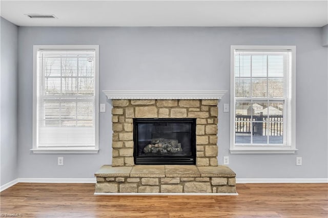 interior details featuring visible vents, a fireplace, baseboards, and wood finished floors