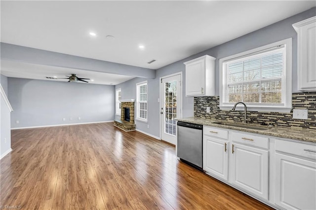 kitchen with tasteful backsplash, a sink, ceiling fan, a fireplace, and stainless steel dishwasher