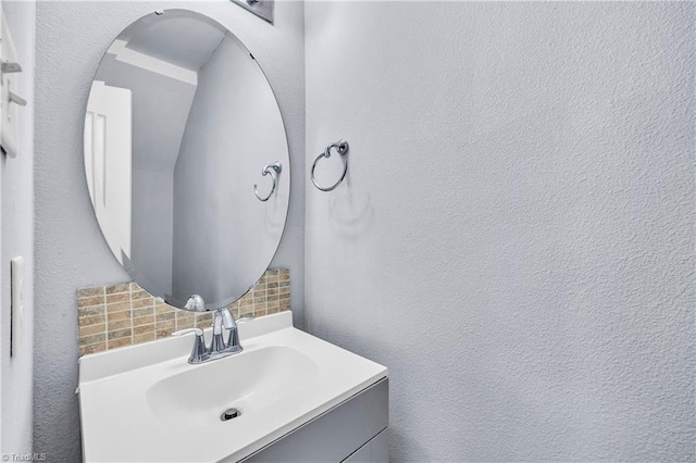 bathroom with tasteful backsplash, vanity, and a textured wall