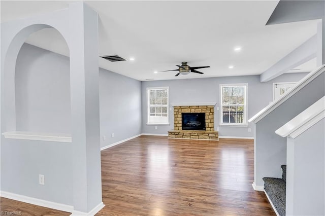 unfurnished living room featuring visible vents, ceiling fan, stairway, a fireplace, and wood finished floors