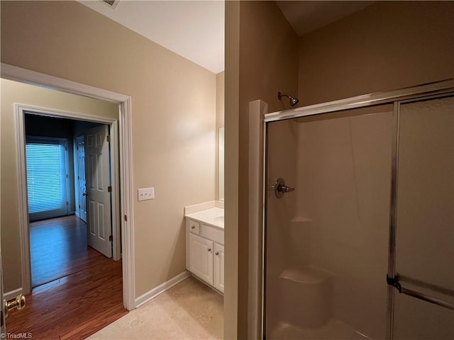 bathroom with hardwood / wood-style flooring, walk in shower, and vanity