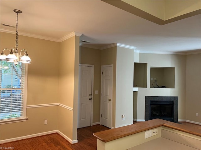 unfurnished living room with an inviting chandelier, dark hardwood / wood-style floors, ornamental molding, and a fireplace