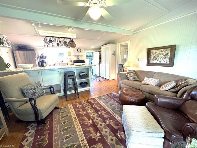 living room featuring a ceiling fan, lofted ceiling with beams, and wood finished floors
