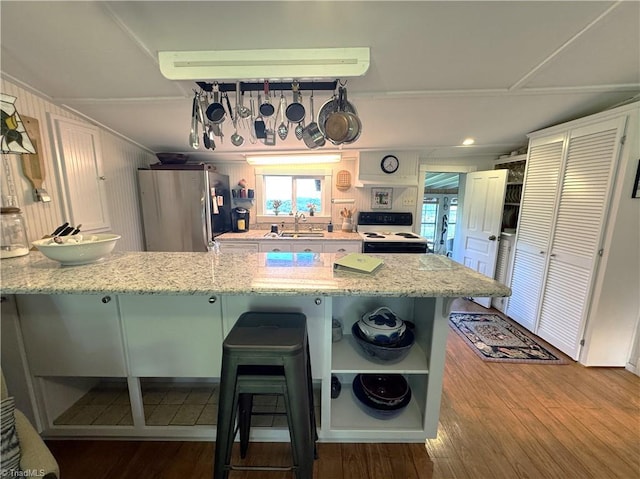 kitchen with open shelves, a peninsula, freestanding refrigerator, a sink, and electric range oven