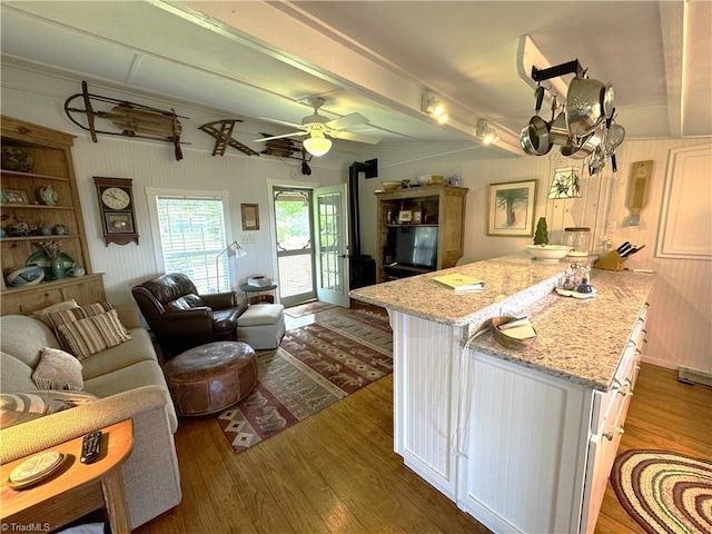 living area with beamed ceiling, ceiling fan, and wood finished floors