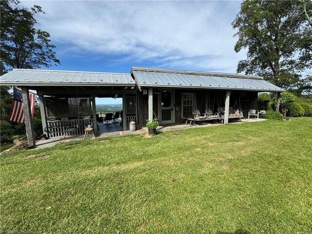 back of property with a yard, a carport, and metal roof