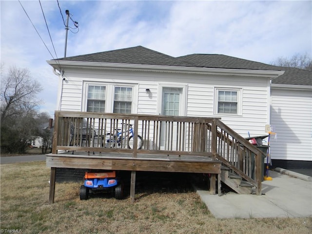 rear view of property featuring a wooden deck and a lawn