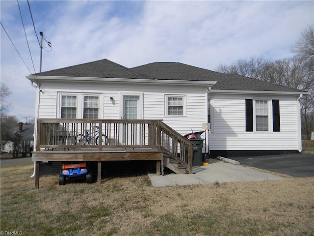 rear view of property with a wooden deck and a lawn