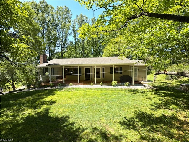 back of house featuring a lawn, covered porch, and a chimney