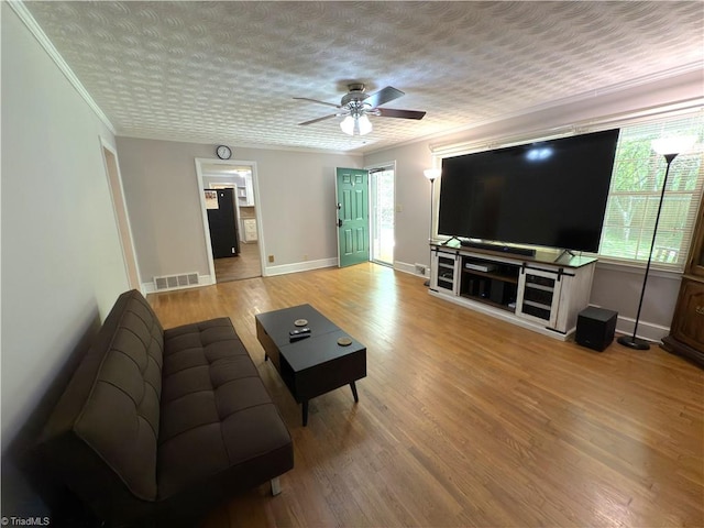 living area featuring a healthy amount of sunlight, baseboards, ceiling fan, and visible vents